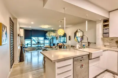 a kitchen with white cabinets and a dining room at Art Deco Broadway Queen Room in Vancouver