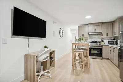 a kitchen with a desk and a tv on the wall at NEST- Modern 2BR Basement Retreat in South Surrey in Surrey