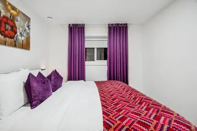 a bedroom with a large bed with purple curtains at NEST- Modern 2BR Basement Retreat in South Surrey in Surrey