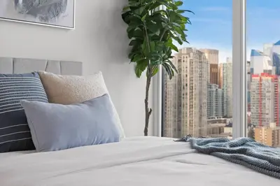 a bedroom with a view of a city from a window at Studio Just Steps from Stampede Park, Luxury Living in Calgary