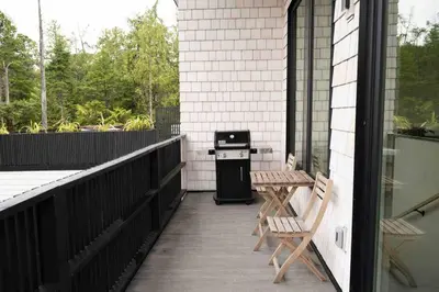 a patio with two benches and a grill on a house at WHITE HAUS w private sauna and close to beach in Ucluelet