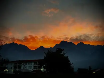 a sunset with mountains in the background and a building at Modern Condo Dream at Fairmont in Fairmont Hot Springs