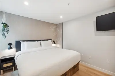 a bedroom with a large white bed and a flat screen tv at The Oak Hotel in Nelson