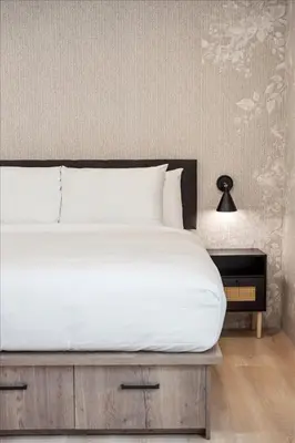 a bedroom with a large bed with white sheets and a lamp at The Oak Hotel in Nelson