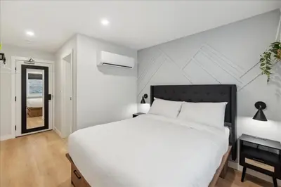 a white bedroom with a large bed and a window at The Oak Hotel in Nelson