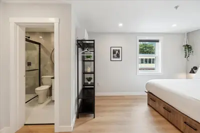 a white bedroom with a bed and a bathroom at The Oak Hotel in Nelson