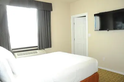 a bedroom with a bed and a window and a television at High Point Inn & Suites Peace River in Peace River