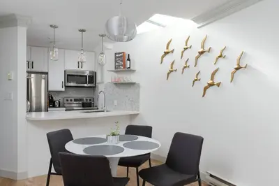 a kitchen with a table and some birds on the wall at Boutique Beach Apartment in Vancouver