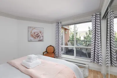 a bedroom with a bed and a large window at Boutique Beach Apartment in Vancouver