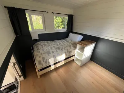 a small bedroom with a bed and two windows at Malaspina Strait Tiny Home in Powell River