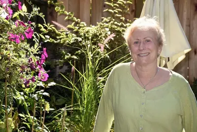 an older woman standing in front of a garden at Ferry Walk House in West Vancouver