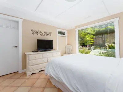 a bedroom with a bed and a tv and a window at Ferry Walk House in West Vancouver