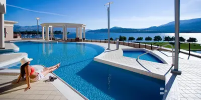 a woman sitting on the edge of a swimming pool at The Royal Kelowna - Bellstar Hotels & Resorts in Kelowna