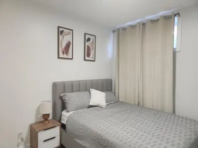 a white bedroom with a bed and a window at Brand New Deluxe 2 Bedroom Suite with AC & Den in Calgary