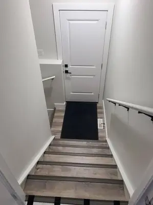 a hallway with a staircase leading to a door at Charming 2-Bedroom Basement Oasis Sleeps 5,Size-150sqm, Netflix, family friendly in Edmonton