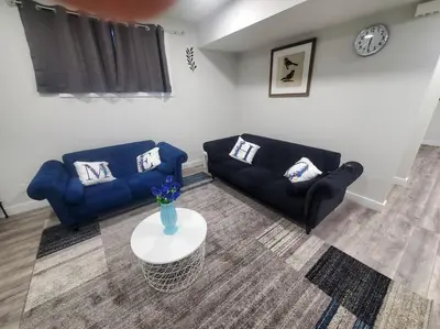 a living room with two blue couches and a table at Charming 2-Bedroom Basement Oasis Sleeps 5,Size-150sqm, Netflix, family friendly in Edmonton