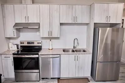 a kitchen with white cabinets and a stainless steel refrigerator at Brand-new three bedroom guest suite in the desirable neighbourhood in Prince George