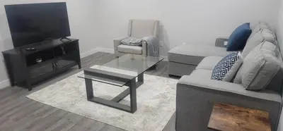 a living room with a couch and a tv and a table at A Cozy home away from home at South East Calgary in Calgary