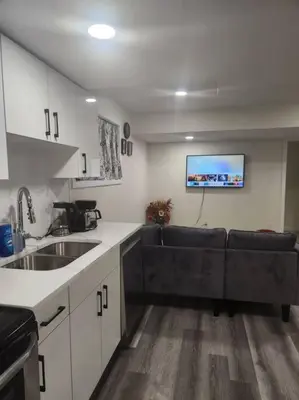 a kitchen with a couch and a tv on the wall at Modern 2 Bedroom Basement Suite Chappelle Edmonton in Edmonton