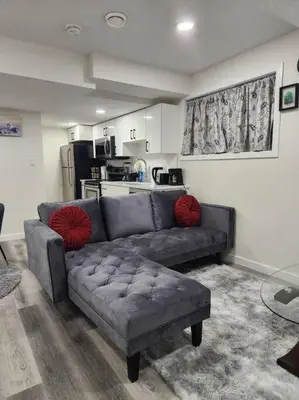 a living room with a gray couch and a kitchen at Modern 2 Bedroom Basement Suite Chappelle Edmonton in Edmonton