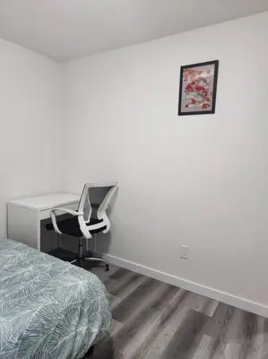 a bedroom with a desk and a chair next to a bed at Modern 2 Bedroom Basement Suite Chappelle Edmonton in Edmonton