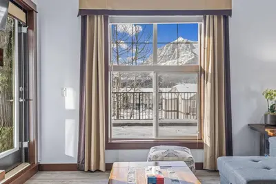 a living room with a large window with a view at S105 Canmore Stay- Hot tub, stream rm, gym, parking Mtn Retreat in Canmore