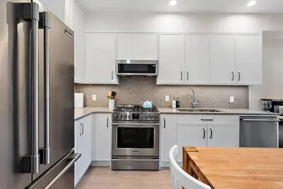 a kitchen with white cabinets and a stainless steel refrigerator at The Beach House at Saratoga Oceanfront Escape in Oyster Bay
