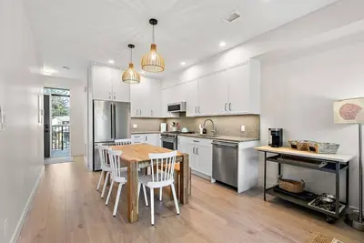 a kitchen with white cabinets and a table and chairs at The Beach House at Saratoga Oceanfront Escape in Oyster Bay