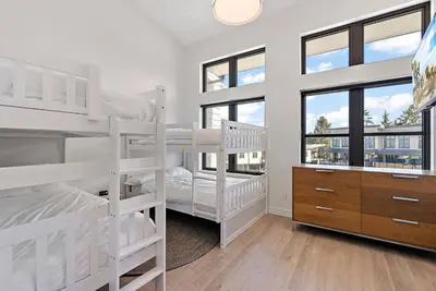 two white bunk beds in a room with windows at The Beach House at Saratoga Oceanfront Escape in Oyster Bay