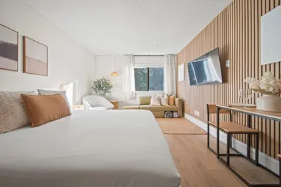 a bedroom with a large bed and a living room at Cozy Creek Den - Updated Nov 2025 in Whistler