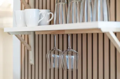 a shelf with cups and wine glasses on it at Cozy Creek Den - Updated Nov 2025 in Whistler