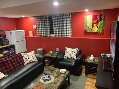 a living room with black leather furniture and red walls at Cozy Lodge Suite in Sylvan Lake