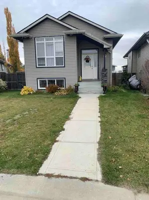 a house with a sidewalk leading to the front door at Cozy Lodge Suite in Sylvan Lake