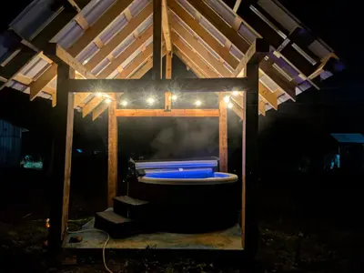a wooden gazebo with a bath tub with lights at Farmhouse cabin on 33 acre farm in Powell River