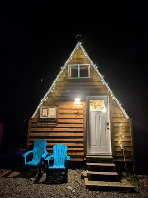 two blue chairs in front of a cabin at night at Farmhouse cabin on 33 acre farm in Powell River