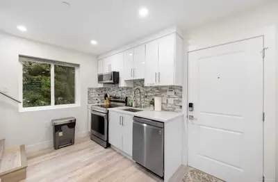 a kitchen with white cabinets and a stove top oven at Entire new small home in Vancouver