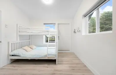 a white bedroom with bunk beds and a window at Entire new small home in Vancouver