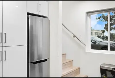 a kitchen with a stainless steel refrigerator next to a window at Entire new small home in Vancouver