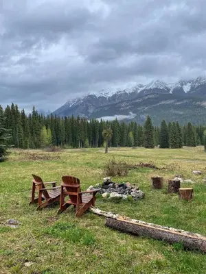 two benches sitting in a field with mountains in the background at Rustic Beaverfoot Lodge Room N3 in Parson