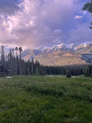a field of grass with mountains in the background at Rustic Beaverfoot Lodge Room N3 in Parson