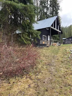 a black barn with a gambrel roof in a field at Rustic Beaverfoot Lodge Room N4 in Parson