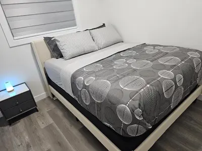 a bedroom with a bed with a black and white comforter at Sleek Home in Trendy Community at SW, Edmonton in Edmonton