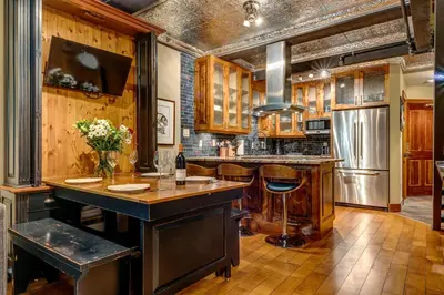 a kitchen with wooden cabinets and a large island with bar stools at Greystone Lodge 320 Ski-in Out in Whistler