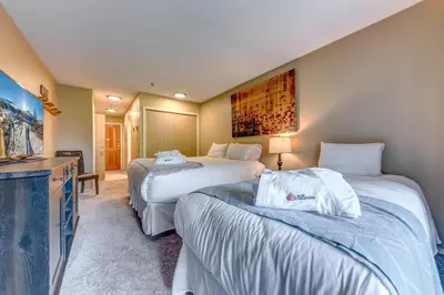 a hotel room with two beds and a television at Greystone Lodge 318 Ski-in Out in Whistler