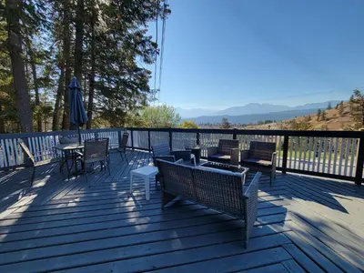 a deck with chairs and tables and an umbrella at Cross Suite - MistyRiver Lodge in Radium Hot Springs
