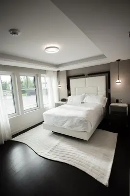 a bedroom with a large white bed and a rug at the reid hotel in Vanderhoof