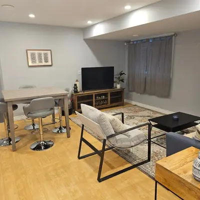 a living room with a television and a table and chairs at River Valley Suite Near Downtown in Edmonton