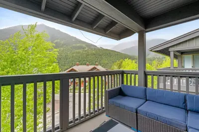 a patio with a blue couch on a balcony with a view at Reach Your Peak, Ski In, Ski Out, Pool, Hot Tub in Panorama