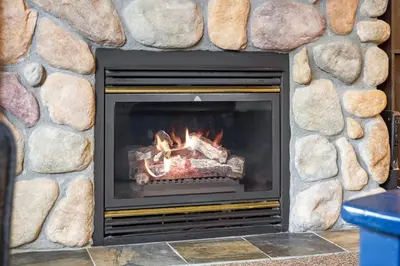 a stone fireplace with a fire in it at Reach Your Peak, Ski In, Ski Out, Pool, Hot Tub in Panorama