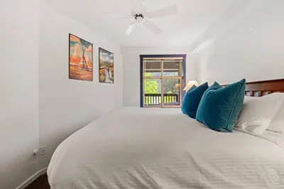 a white bedroom with a large bed with blue pillows at Reach Your Peak, Ski In, Ski Out, Pool, Hot Tub in Panorama